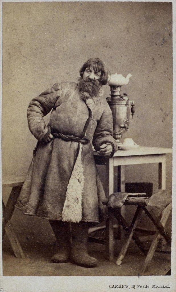 Бородатый мужик рядом с самоваром.